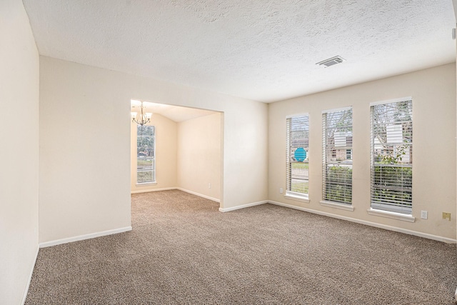 carpeted empty room featuring a chandelier, visible vents, a textured ceiling, and baseboards