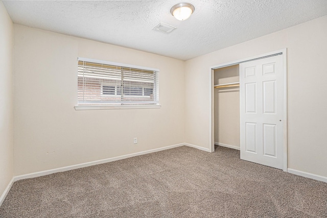 unfurnished bedroom with visible vents, baseboards, a textured ceiling, carpet flooring, and a closet