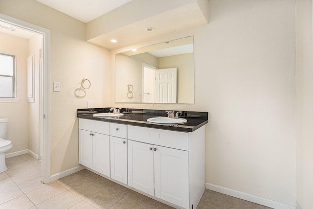 full bath featuring baseboards, a sink, toilet, and double vanity