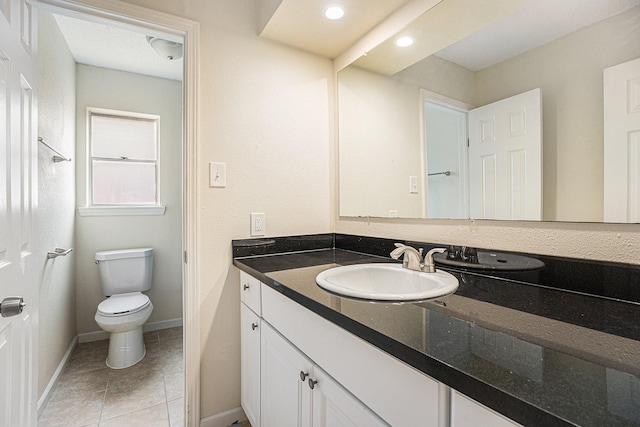 bathroom featuring baseboards, vanity, toilet, and tile patterned floors