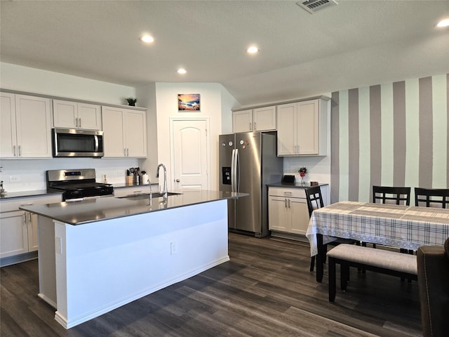 kitchen featuring dark wood-style floors, stainless steel appliances, dark countertops, and a sink