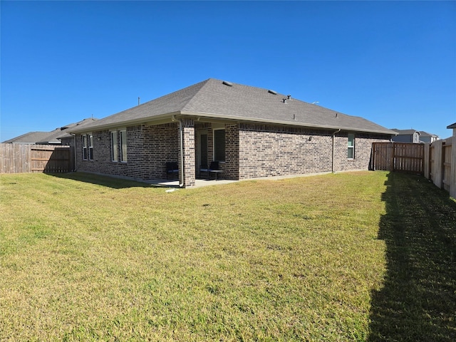 rear view of house with a patio, brick siding, a lawn, and a fenced backyard