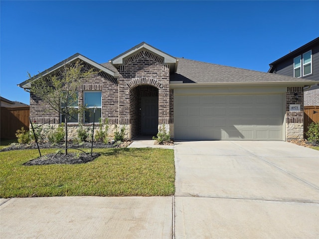 view of front facade featuring brick siding, concrete driveway, an attached garage, a front yard, and fence