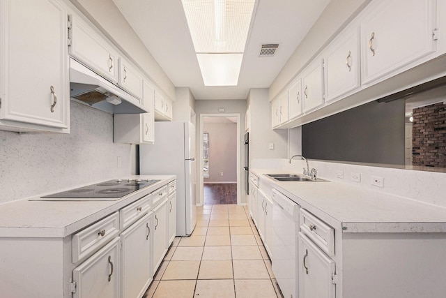 kitchen featuring white appliances, under cabinet range hood, light countertops, and a sink