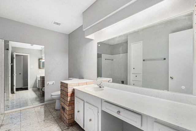 bathroom featuring toilet, visible vents, a tile shower, and vanity