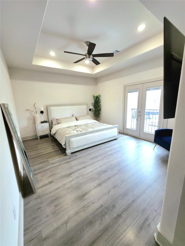 unfurnished bedroom featuring french doors, recessed lighting, a raised ceiling, light wood-style floors, and access to outside