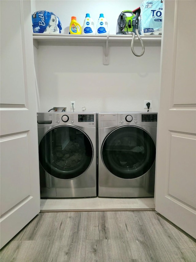 laundry room with laundry area, independent washer and dryer, and light wood-style flooring