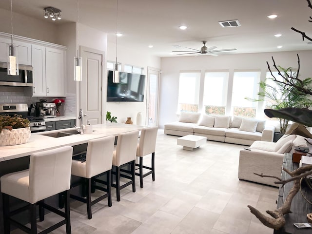 kitchen featuring light stone counters, a breakfast bar, hanging light fixtures, appliances with stainless steel finishes, and open floor plan