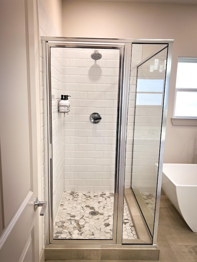 full bath featuring tile patterned flooring, a freestanding tub, and a shower stall