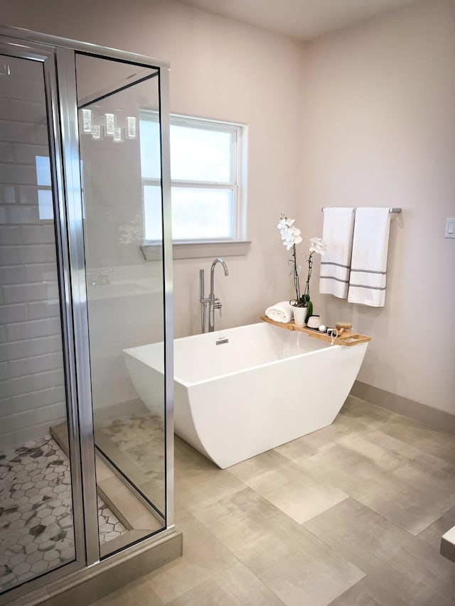 bathroom featuring baseboards, a freestanding tub, and a shower stall