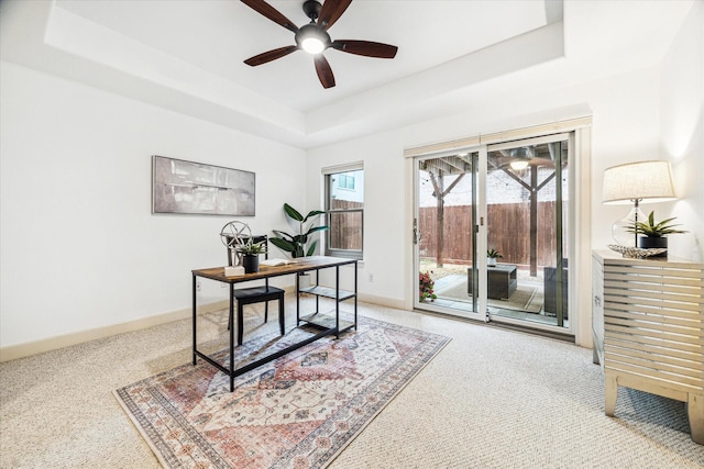 home office featuring baseboards, a raised ceiling, and a ceiling fan