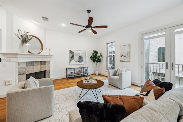 living area featuring baseboards, visible vents, a tile fireplace, wood finished floors, and french doors