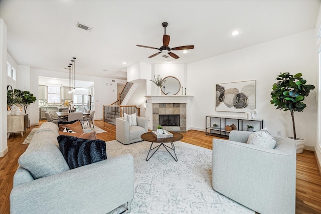 living area with light wood-style flooring, stairs, visible vents, and a tile fireplace