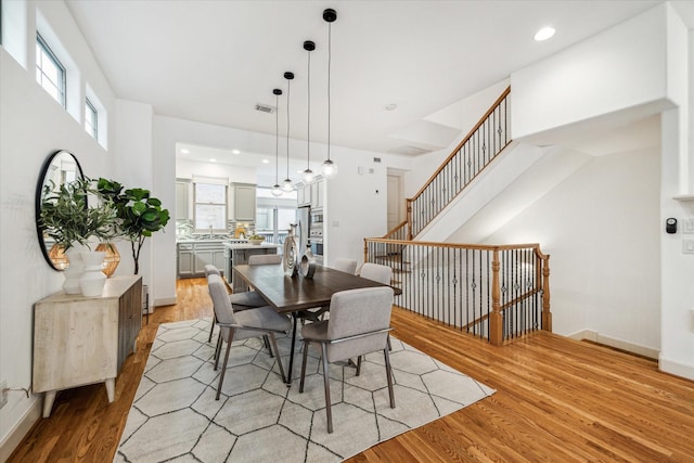 dining room featuring light wood-style flooring, recessed lighting, visible vents, baseboards, and stairs