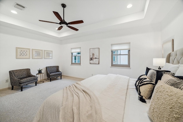 carpeted bedroom featuring recessed lighting, a raised ceiling, visible vents, and baseboards