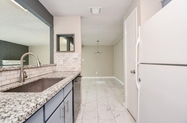 kitchen featuring visible vents, dishwasher, freestanding refrigerator, marble finish floor, and a sink