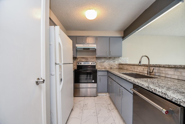 kitchen featuring under cabinet range hood, a sink, marble finish floor, appliances with stainless steel finishes, and light stone countertops