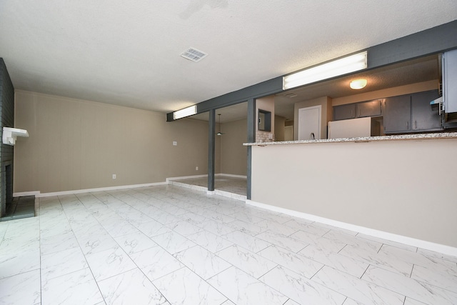 unfurnished living room with marble finish floor, a fireplace, visible vents, a textured ceiling, and baseboards