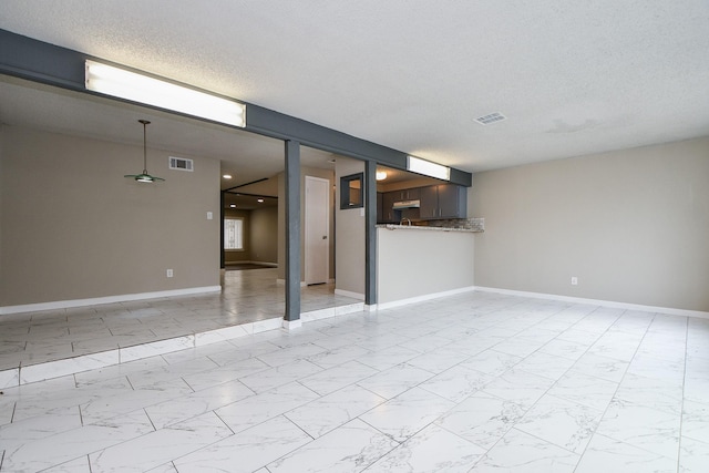 spare room featuring a textured ceiling, marble finish floor, visible vents, and baseboards