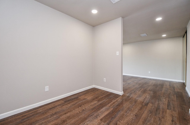 unfurnished room featuring dark wood-style floors, visible vents, baseboards, and recessed lighting