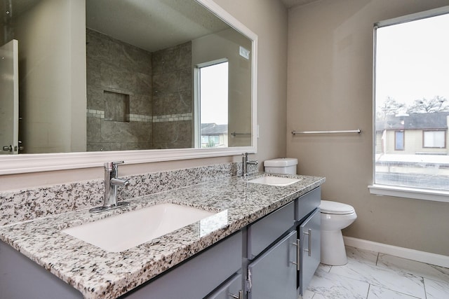 bathroom with toilet, marble finish floor, baseboards, and a sink