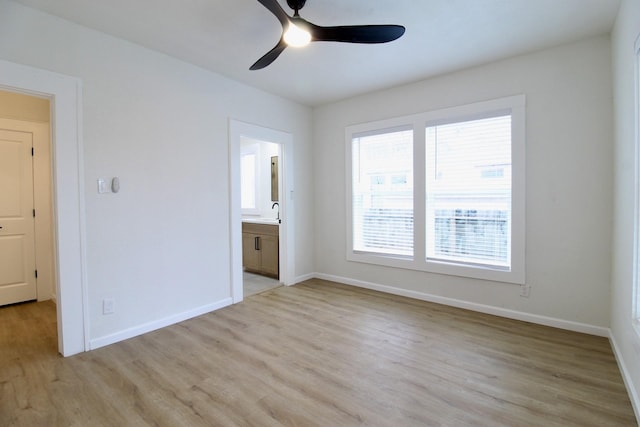 unfurnished bedroom with ceiling fan, ensuite bath, light wood-style flooring, and baseboards