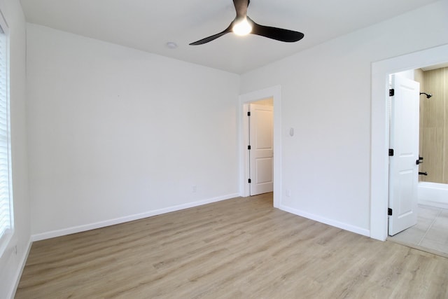 interior space with light wood-type flooring, ceiling fan, baseboards, and ensuite bathroom