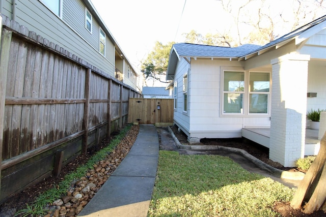 view of home's exterior with brick siding, a fenced backyard, and roof with shingles