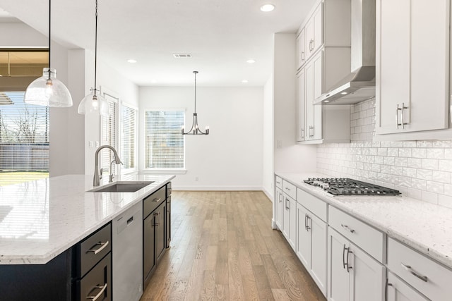 kitchen with white cabinets, wall chimney exhaust hood, appliances with stainless steel finishes, dark cabinets, and pendant lighting