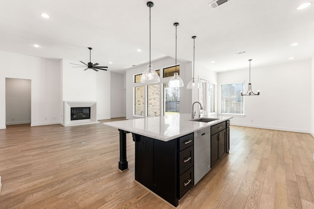 kitchen featuring hanging light fixtures, open floor plan, a sink, an island with sink, and dishwasher