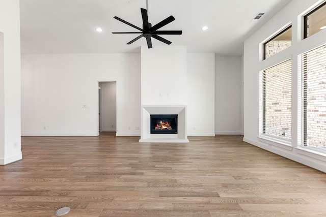 unfurnished living room featuring light wood finished floors, a lit fireplace, and recessed lighting