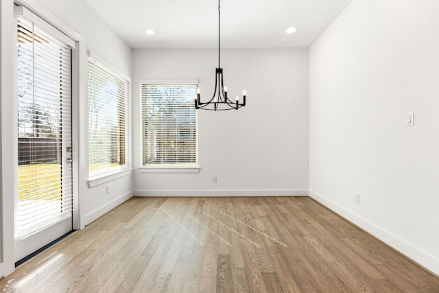 unfurnished dining area featuring baseboards, recessed lighting, a notable chandelier, and light wood-style floors