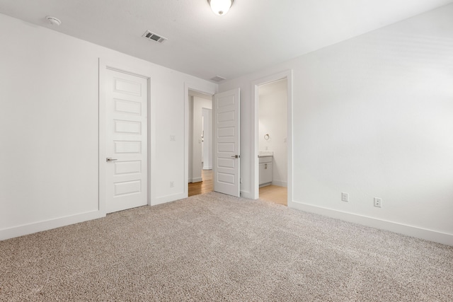 unfurnished bedroom with light carpet, connected bathroom, visible vents, and baseboards