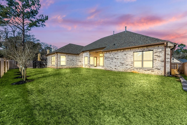 rear view of property featuring a fenced backyard, roof with shingles, and a yard