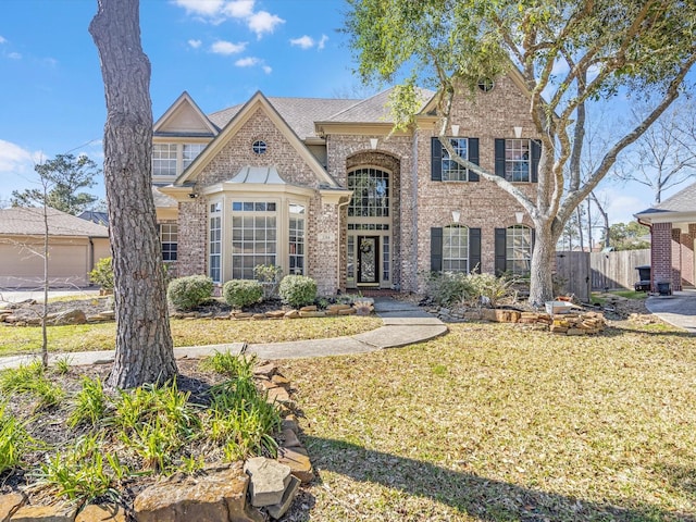 traditional-style home featuring a front yard, brick siding, and fence