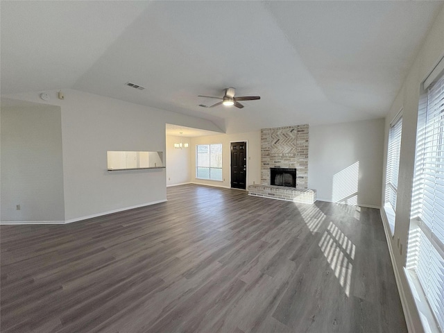 unfurnished living room featuring a large fireplace, visible vents, a ceiling fan, dark wood-style floors, and vaulted ceiling