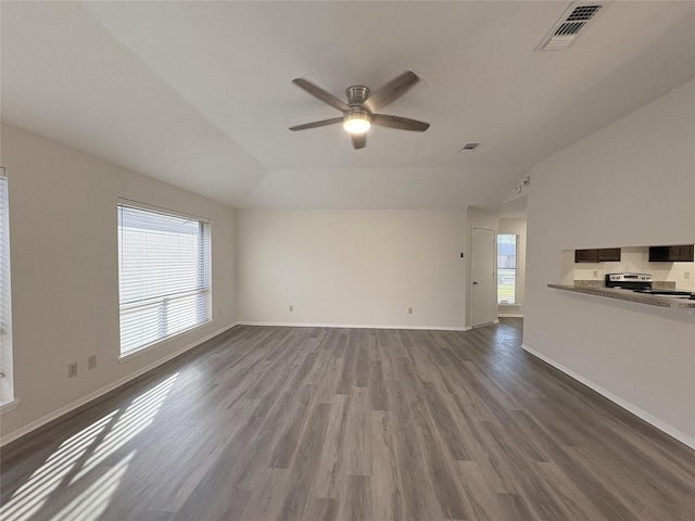 unfurnished living room featuring a raised ceiling, visible vents, ceiling fan, wood finished floors, and baseboards