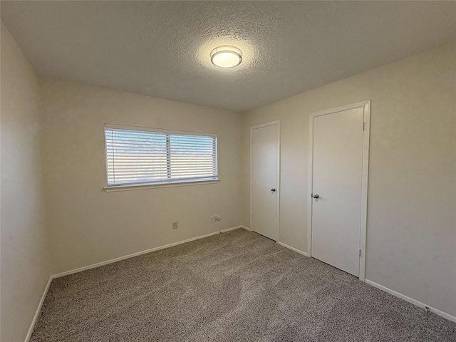 unfurnished bedroom featuring carpet floors, baseboards, and a textured ceiling