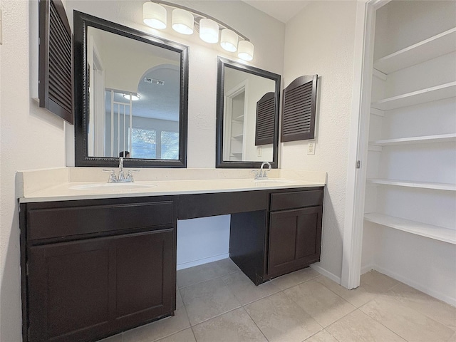 full bathroom with tile patterned flooring, a sink, a spacious closet, and double vanity