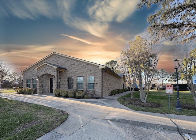 view of front of property with brick siding, driveway, and a front lawn