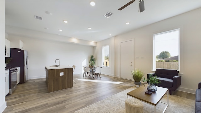 living area with light wood-style flooring, visible vents, and recessed lighting