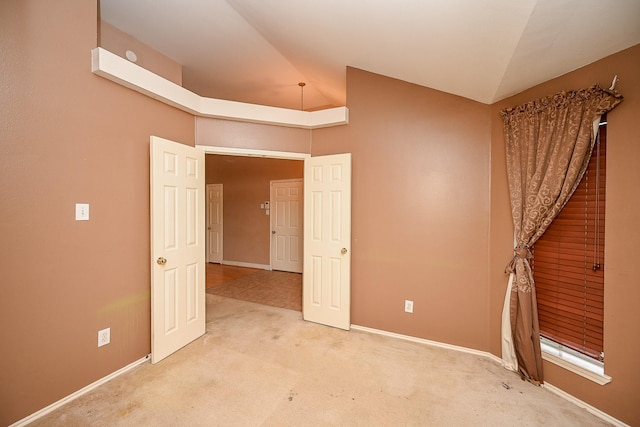 empty room with lofted ceiling, baseboards, and light colored carpet