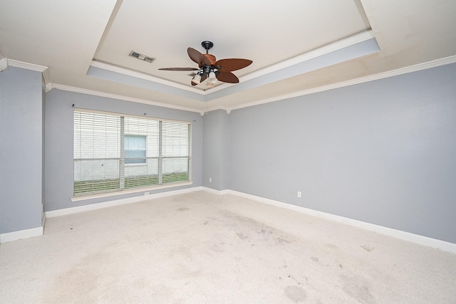 carpeted empty room with visible vents, baseboards, a raised ceiling, and crown molding