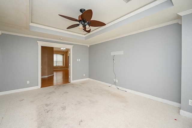 carpeted empty room with crown molding, ceiling fan, a tray ceiling, and baseboards