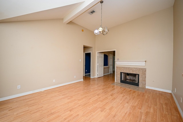 unfurnished living room with a tile fireplace, visible vents, baseboards, beam ceiling, and light wood finished floors