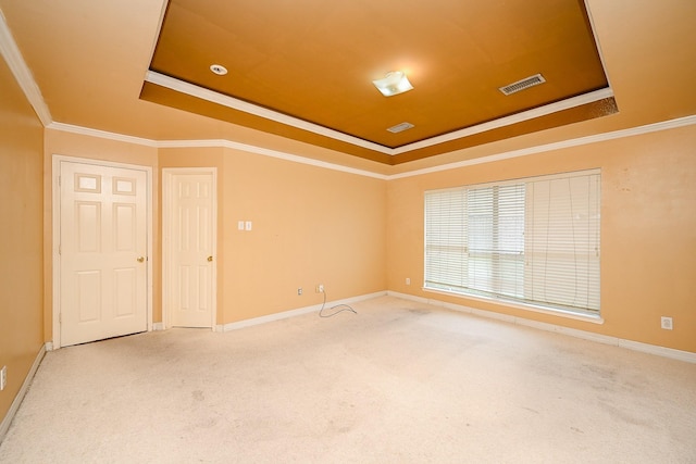 spare room with ornamental molding, carpet flooring, a raised ceiling, and visible vents