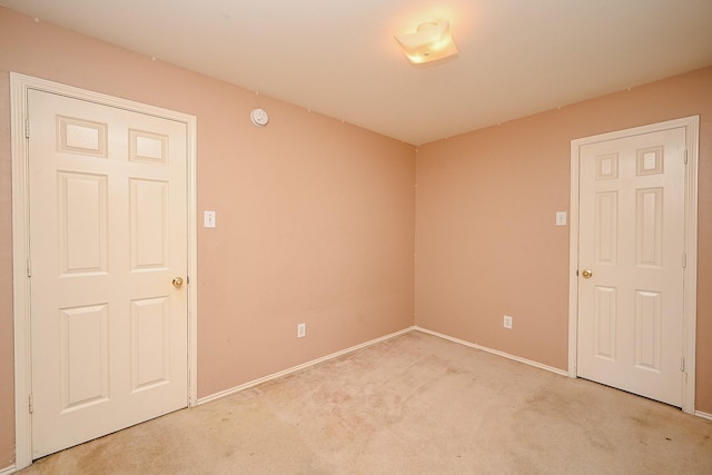 unfurnished room with baseboards and light colored carpet