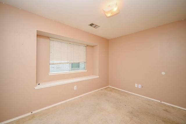 unfurnished room with baseboards, visible vents, and light colored carpet