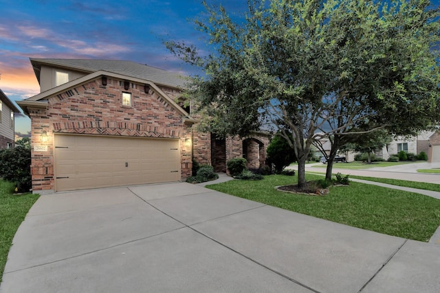 view of front of house with a garage, a lawn, concrete driveway, and brick siding