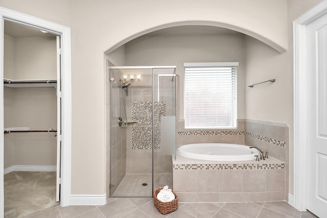 full bathroom featuring a shower stall, a garden tub, tile patterned flooring, a walk in closet, and baseboards